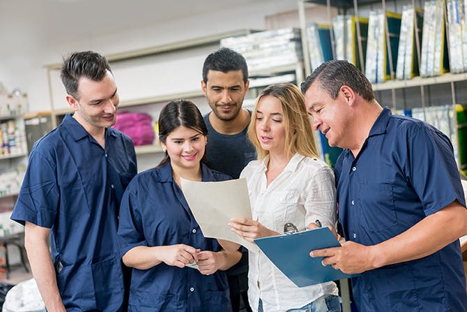 business owner with cleaning crew looking at schedule of work documents
